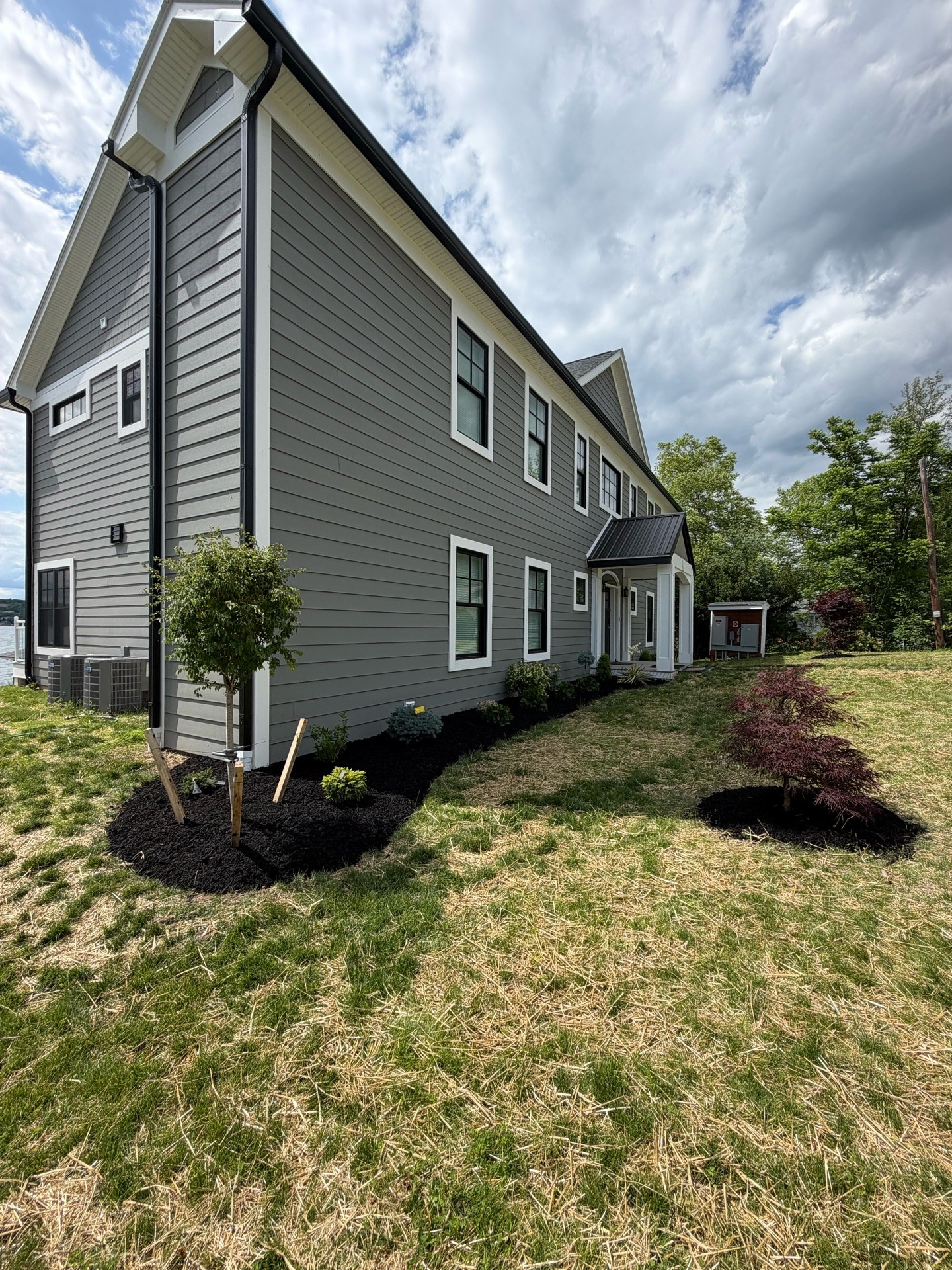 New landscape installation at a Canandaigua Lake home — edged beds, fabric, mulch and fresh plantings (After 1)