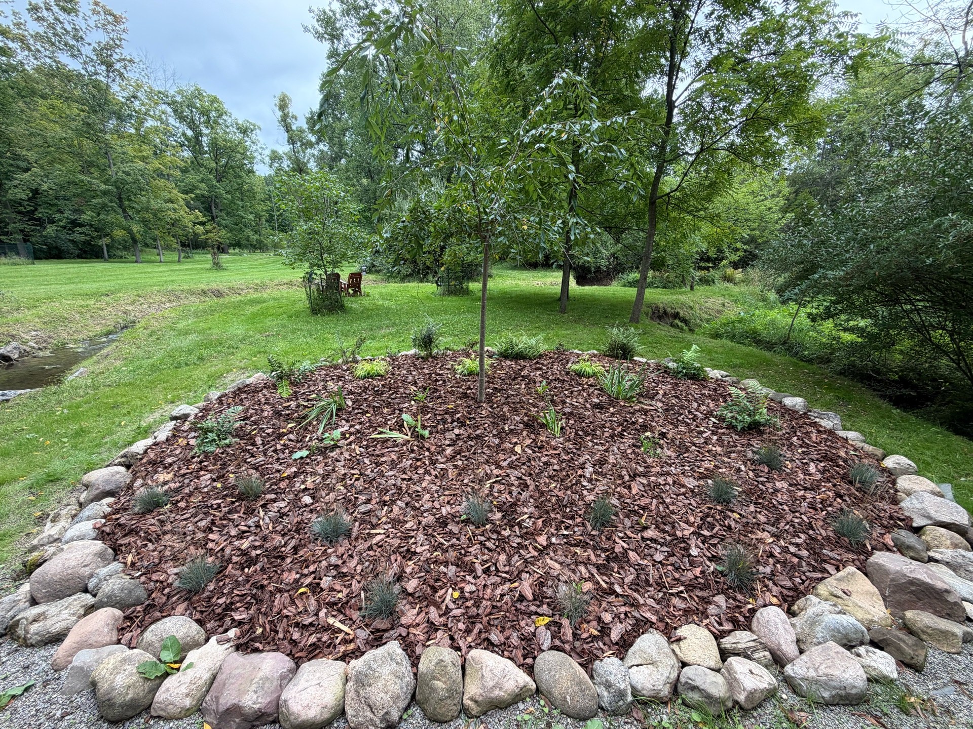 Small garden bed redesign — releveled, new fabric, boulders reset by machine, new plants and pine bark mulch (After 1)