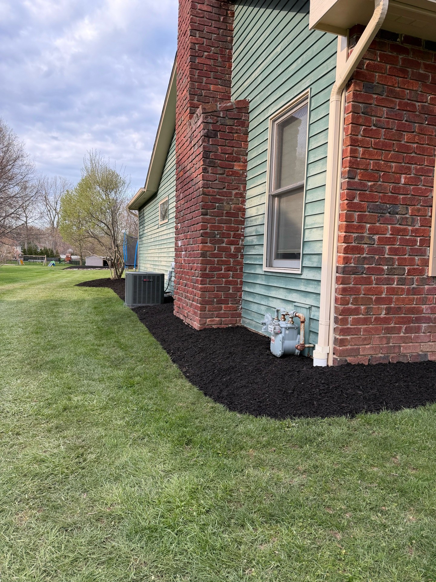 New landscape beds cut and defined, sod removed, professional landscape fabric and fresh mulch (After 1)